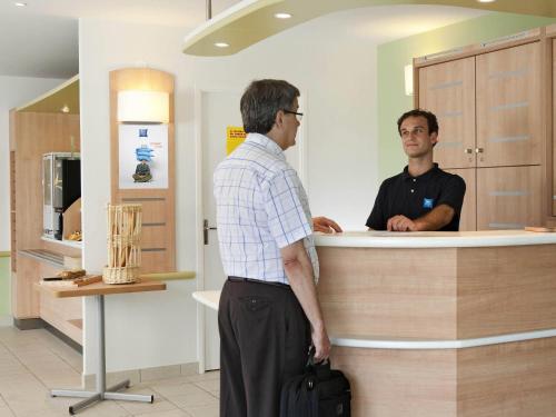 two men standing at a counter in a store at ibis budget Dresden Kesselsdorf in Wilsdruff