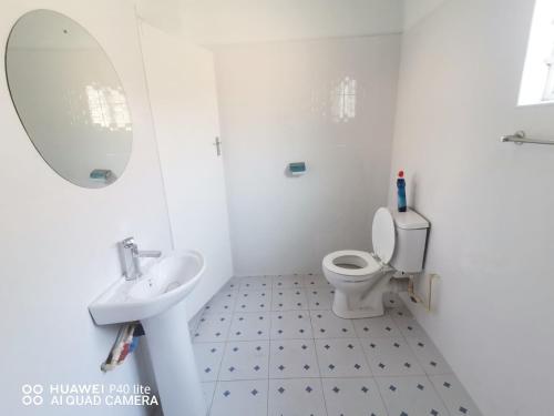 a white bathroom with a sink and a toilet at Wamz Apartments And Tours B in Livingstone