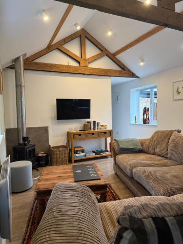 a living room with two couches and a flat screen tv at Beautiful Barn Conversion Wyboston in Bedford
