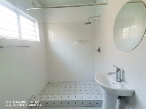 a white bathroom with a sink and a mirror at Wamz Apartments And Tours B in Livingstone
