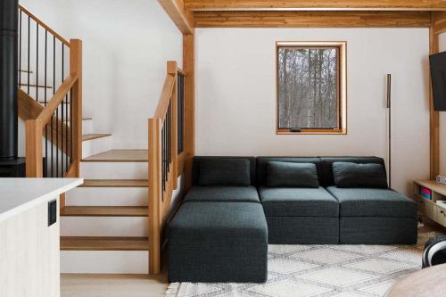 a living room with a couch and a staircase at Camp Haliburton - Waterfront A-Frame in Wilberforce