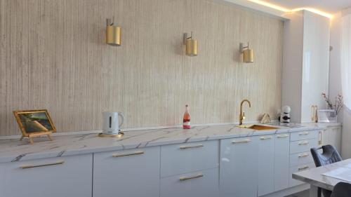a kitchen with white cabinets and a sink at Penthouse Râșnov 80mp, balcon 30mp in Râşnov