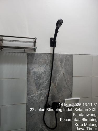 a shower in a bathroom with a black hose at Neomi Homestay Malang in Wendit