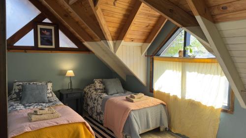 a attic bedroom with two beds and a window at Cabaña "House" in El Chalten