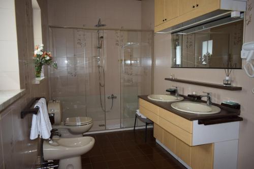 Un baño con dos lavabos y una ducha y un inodoro. en Villa Francesca Luxury Rooms, en San Demetrio Corone