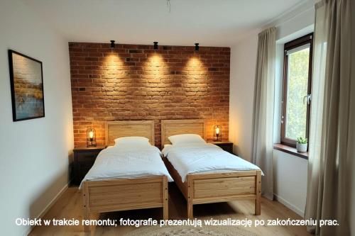 two beds in a bedroom with a brick wall at Lawendowy Domek agroturystyka, noclegi - okolice Bałtowa in Bałtów
