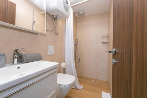 a bathroom with a toilet and a sink and a shower at Apartmani Jakiruša in Brela
