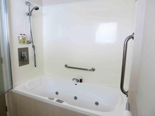 a white bath tub in a bathroom with a shower at ASURE Ascot Motor Inn in Taupo