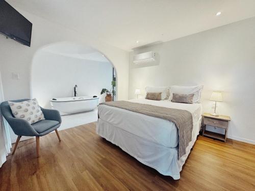 a bedroom with a bed and a tub and a chair at Pousada Ilha do Vento in São Miguel do Gostoso