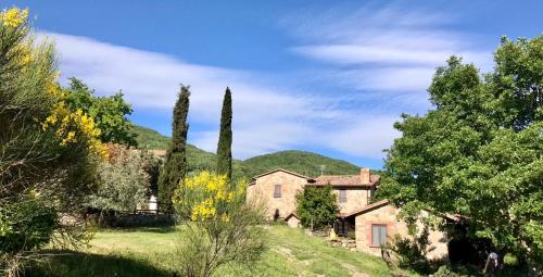 a large stone house on a hill with trees at Agriturismo Melodie Toscane Sorano in Sorano
