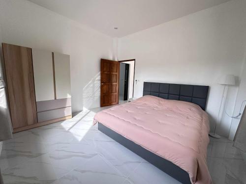 a bedroom with a pink bed in a white room at Grandma Samui Garden in Ban Tai