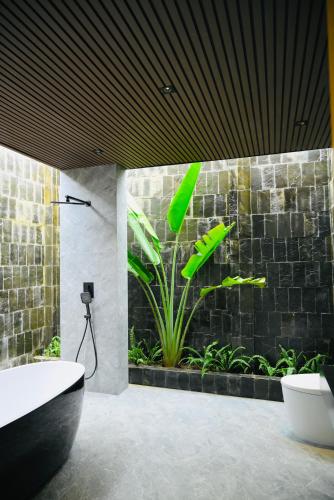 a bathroom with a bath tub and a plant at Biển Tôm ốc Homestay Bến Tre - Hồ Bơi & BBQ Garden in Ấp Sơn Thuận (2)