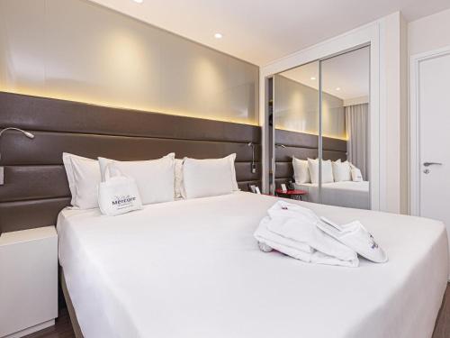 een slaapkamer met een groot wit bed met handdoeken erop bij Mercure Sao Paulo Vila Olimpia in Sao Paulo