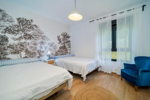 a bedroom with two beds and a blue chair at Villa May en Riegu Vidiago Llanes in Vidiago