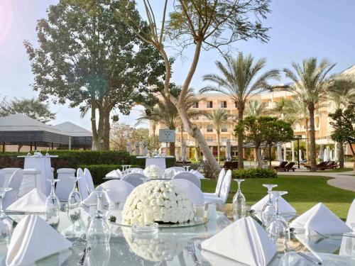a table with white chairs and a cake on it at Novotel Cairo 6th Of October in 6th Of October