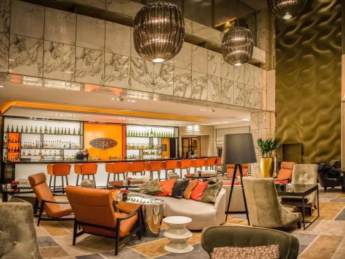 a lobby with a couch and chairs and a bar at Sofitel Warsaw Victoria in Warsaw