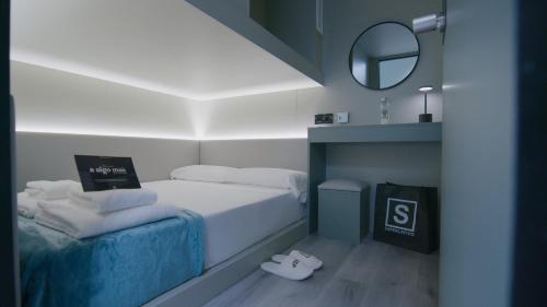 a small bedroom with a bed and a mirror at Hostal Superlativo Trinidad in Málaga