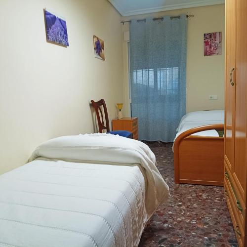 a bedroom with two beds with white sheets and a window at Almansasalud in Cazorla