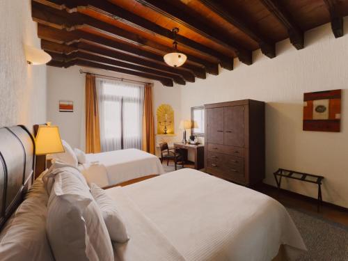 a hotel room with two beds and a desk at Hotel Hacienda la Venta in San Juan del Río