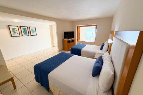 een hotelkamer met twee bedden en een televisie bij Ocean view, beach access & amenities! in Puerto Vallarta