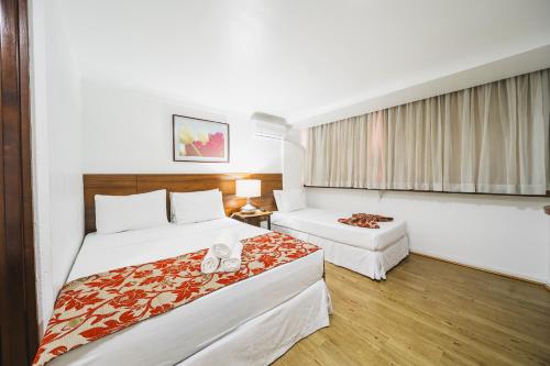 a hotel room with two beds and a table at Hotel Dan Inn Curitiba Centro By Nacional Inn in Curitiba