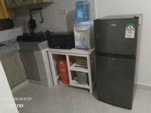 a small kitchen with a refrigerator and a microwave at Prift Royal Apartments in Meru