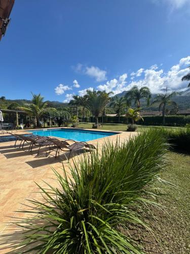 a swimming pool with tables and chairs and palm trees at Recanto Vale Minã in Lavrinhas