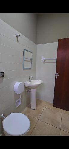 a bathroom with a white sink and a toilet at Hotel Barretos Express in Barretos