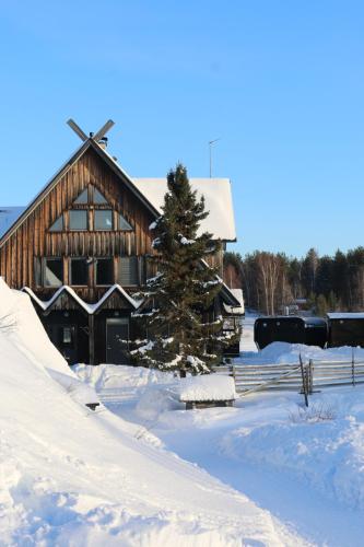 um celeiro coberto de neve com uma árvore de Natal em frente a ele em Shaman Village - Resort & Glass Igloos em Rovaniemi