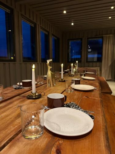 una larga mesa de madera con platos y velas. en Shaman Village - Resort & Glass Igloos, en Rovaniemi