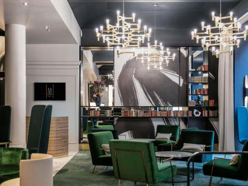 a waiting room with green chairs and a chandelier at Century Old Town Prague - MGallery Collection in Prague