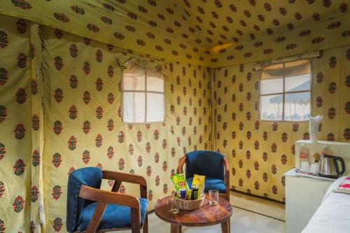 two chairs and a table in a room with wallpaper at Dunes Heritage Desert Camp in Jaisalmer