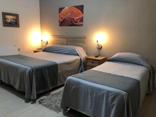 two beds in a hotel room with two lamps at Hotel Durazno in Durazno