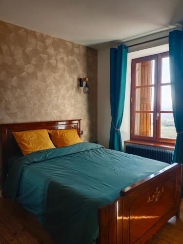 a bedroom with a bed and a window with blue curtains at La petite Maison in Vézézoux