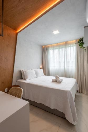 a bedroom with a large white bed with a window at Camurim Residence in Maragogi