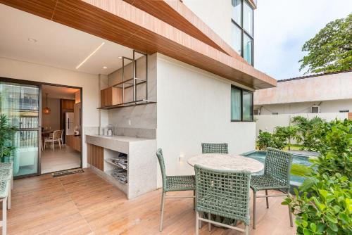 eine Außenterrasse mit einem Tisch und Stühlen in der Unterkunft Apto Praia Barra Grande, Camurim Residence in Maragogi