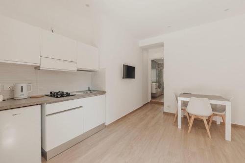 a kitchen with white cabinets and a table and chairs at Bedda Apartment in Cefalù