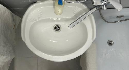 a white bathroom sink with a toothbrush in it at Minimalist 2-room Apartment in Aktobe