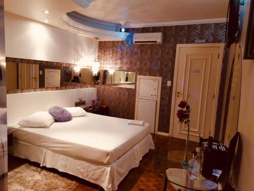 a bedroom with a large white bed and a table at Exos Castelinho Motel in Concordia