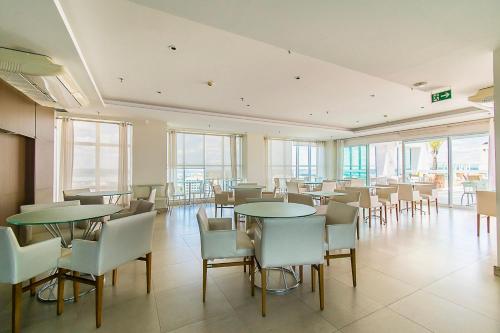 a dining room with tables and chairs and windows at Saint Moritz Hotel em Brasília 63873 in Brasilia