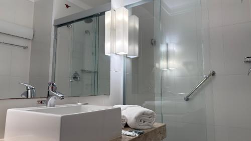 een witte badkamer met een wastafel en een douche bij Prime - Stay Santos in Santos