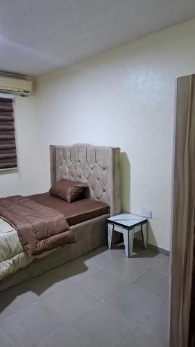 a bed in a room with a table next to it at Rennyshouse 3 Bedroom Apartments in Alimosho
