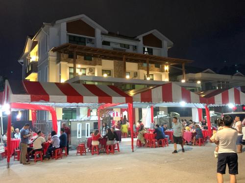 a group of people standing outside a restaurant at night at Woon Homestay in Balik Pulau