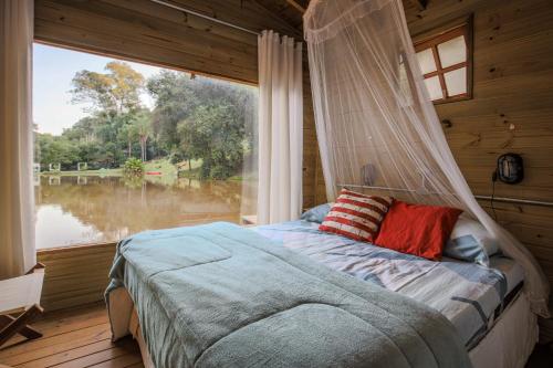 a bed in a room with a large window at Casa Flutuante do Lago Cachoeira, Caiaque, Stand UP e Piscina Quinta do Vale in Itatiba