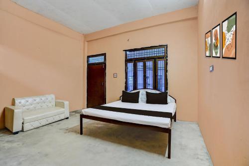 a bedroom with a bed and a couch and a window at Hotel O Guru in Jhūsi