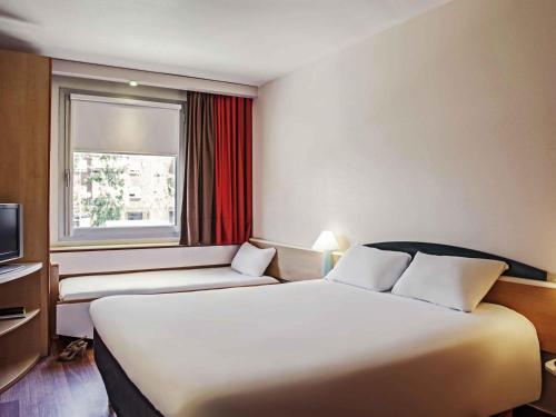 a hotel room with a large bed and a window at Ibis Barcelona Molins de Rei in Molins de Rei