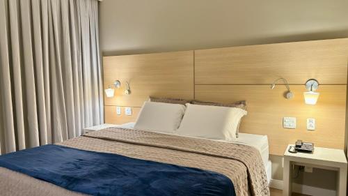 een slaapkamer met een groot bed met een houten hoofdeinde bij Prime - Stay Santos in Santos