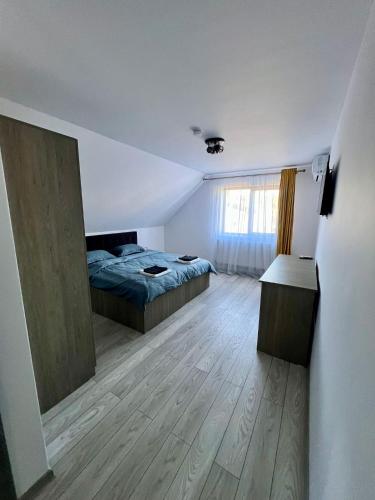 a bedroom with a bed and a wooden floor at La Izvor Moinești, Cazare in Moineşti