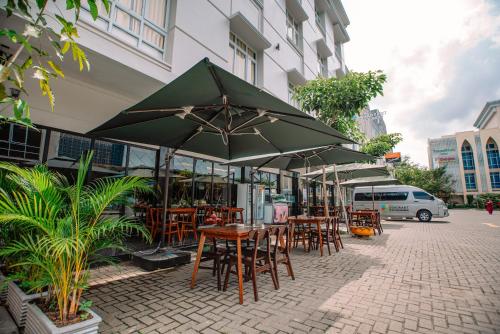 a group of tables and chairs with umbrellas on a street at The Quadrant Hotel KNO in Medan