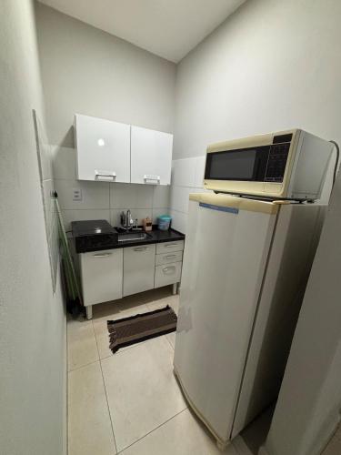 a kitchen with a microwave on top of a refrigerator at Loft próx. Amaral C. e Shopping in Jaú